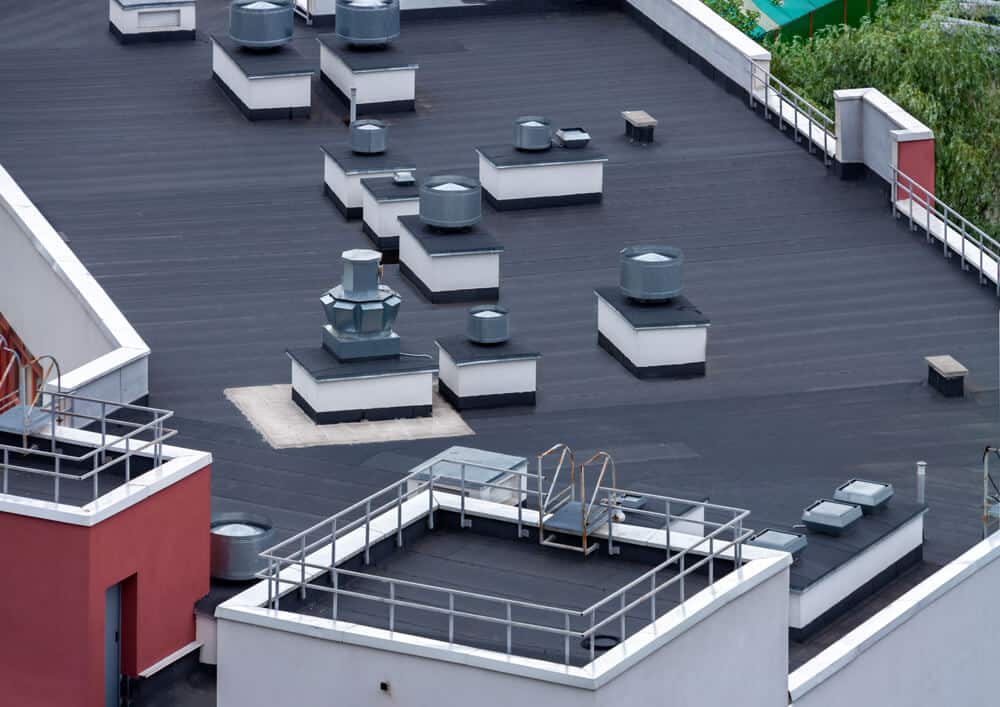 A black modified bitumen roofing system installed on a red commercial building.