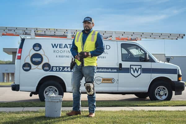 A roofing crew member standing by van before roof installation
