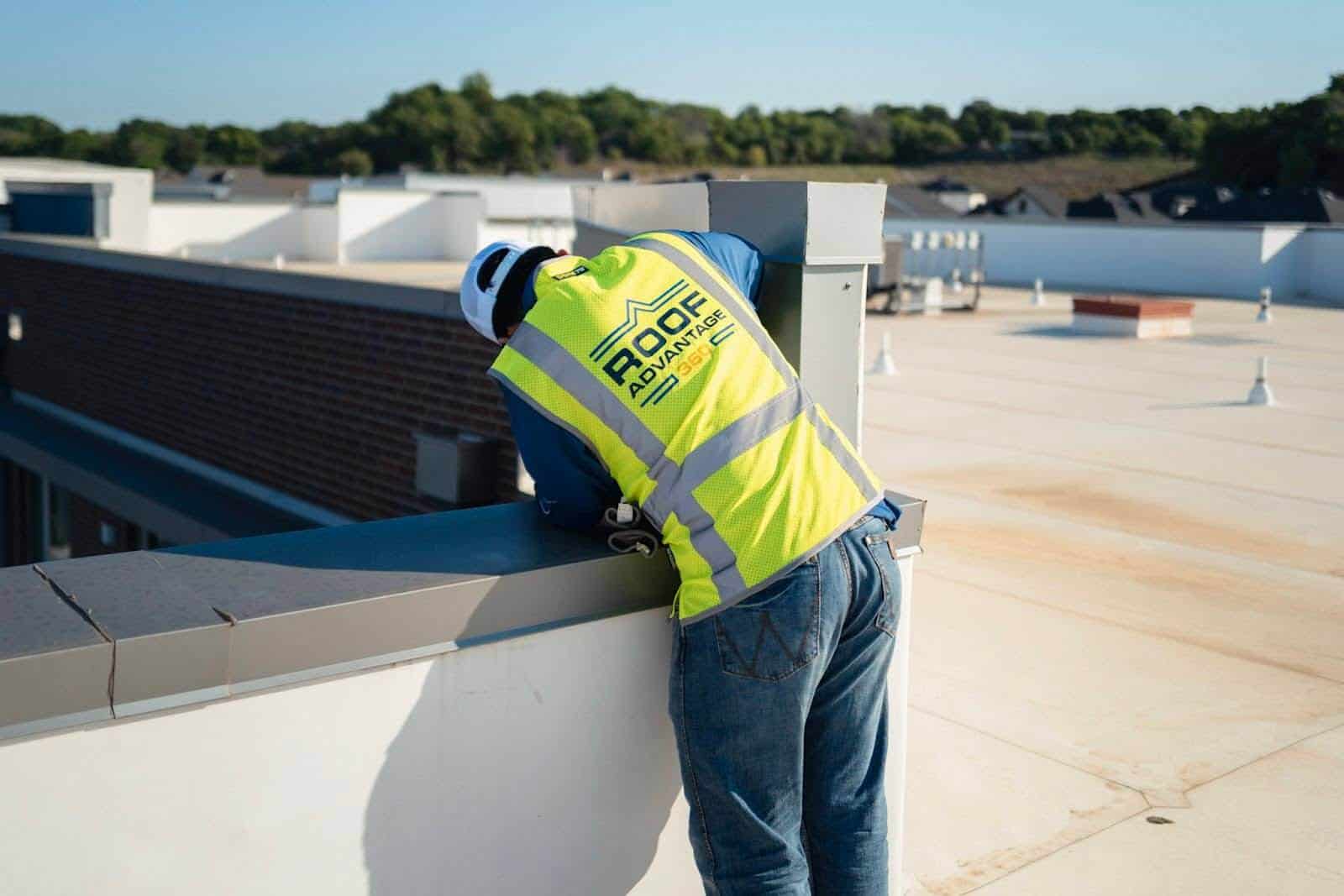 Inspecting the side of a roof on a flat commercial rooftop