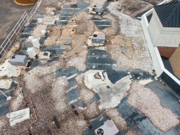 Aging commercial roof showing widespread surface wear and deterioration that may require full roof replacement instead of continued repairs